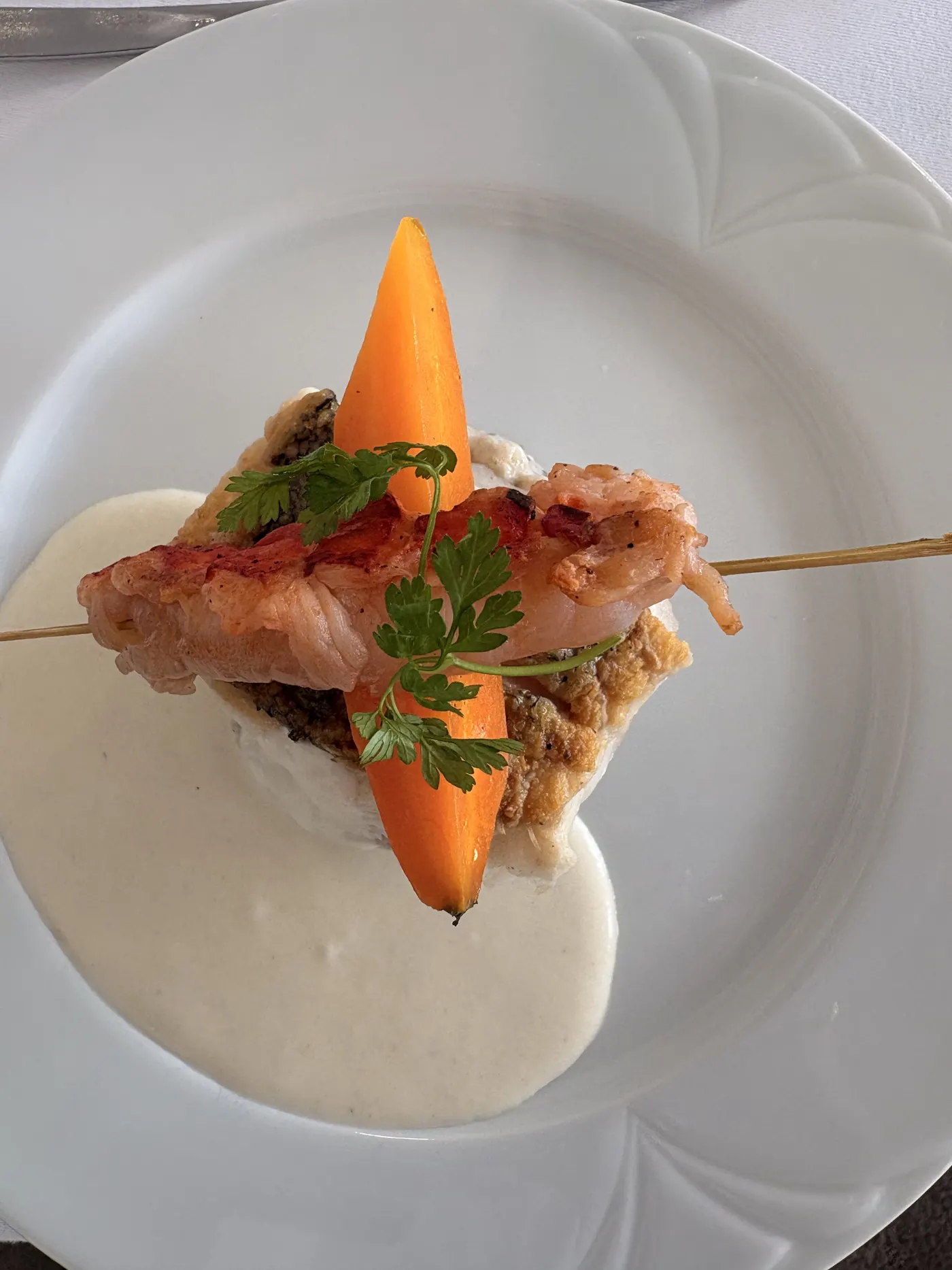 Langoustine dressée sur une crème, carotte glacée et herbes